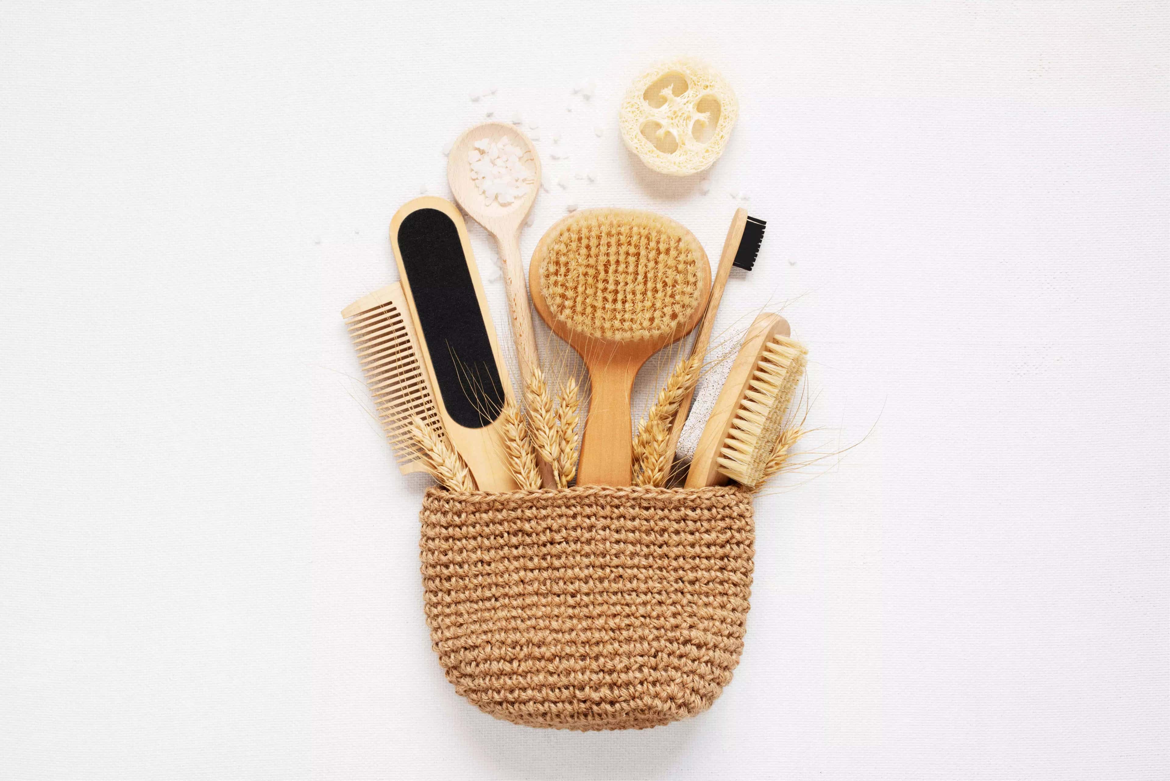 Sacola de palha composta por escova de dente, escova e pente para cabelo, lixa para pés, colher de madeira e uma outra escova para banho.